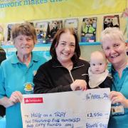 Brontë Sykes and her son Vincent and friend Stephen Jennings hand over a cheque to Hug on a Tray volunteers