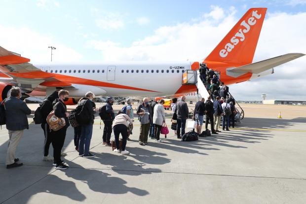Ilkley Gazette: People queue to board an EasyJet plane. (PA)