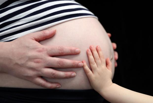 Ilkley Gazette: A child touching a pregnant woman's stomach. Credit: PA