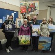 Menston Arts Club members lift their work after a kind but constructive crit night by John Ridyard the renowned Yorkshire artist. Sue Brearley centre back holding one of John's wonderful train studies.