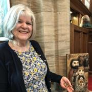 Church member Patsy Bastow holding a tiny nativity scene inside a walnut shell contrasted with a large one carved from a block of wood